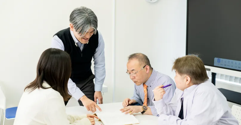 大学のゼミ室で指導する教員と学生たち